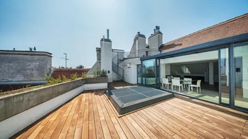 Sonnige Dachterrasse mit Holzdeck, Glasfassade und Wendeltreppe, ideal für Entspannung und Mahlzeiten im Freien.