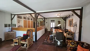 Rustikaler offener Wohn- und Essbereich mit Holzbalken, Terrakottaboden und traditionellen Möbeln.