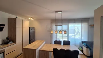 Heller offener Wohn- und Essbereich mit moderner Küche, Holzboden und Zugang zum Wohnzimmer.
