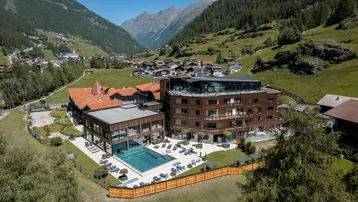 Luxuriöses Hotelgebäude in alpiner Landschaft mit Außenpool und Bergblick.