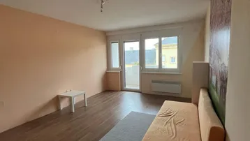 Helles Wohnzimmer mit Holzboden, Balkonzugang und einer auffälligen floralen Tapete an der Wand.