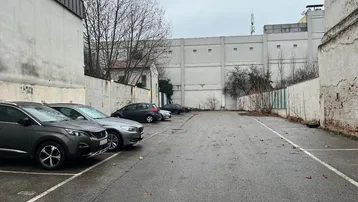 Außenbereich mit Parkplätzen und umliegenden Gebäuden an einem bewölkten Tag.