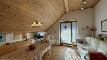 Gemütlicher Wohn-Essbereich im Dachgeschoss mit Holzbalkendecke und viel Tageslicht.