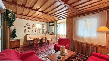 Gemütlicher Wohn- und Essbereich im Landhausstil mit viel Holz und traditionellen Teppichen.