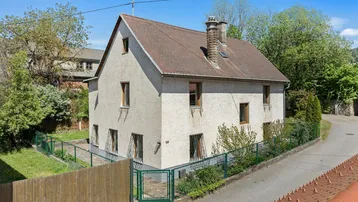Freistehendes Einfamilienhaus mit Satteldach und gepflegtem Vorgarten in ländlicher Umgebung.