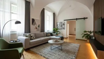 Helles Wohnzimmer mit Gewölbedecke, Holzboden und moderner Einrichtung.