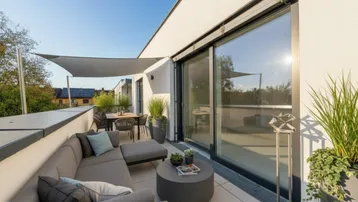 Geräumige Dachterrasse mit moderner Lounge-Sitzgruppe, Esstisch und Sonnensegel für entspannte Stunden im Freien.