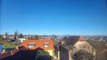 Panoramablick über eine Wohnsiedlung mit roten Dächern und blauer Himmel im Hintergrund.