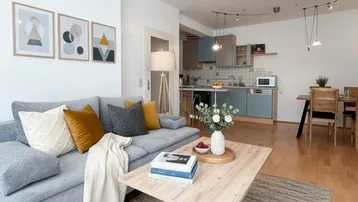 Heller offener Wohn-Essbereich mit moderner Einrichtung, bequemer Couch und Holzboden.