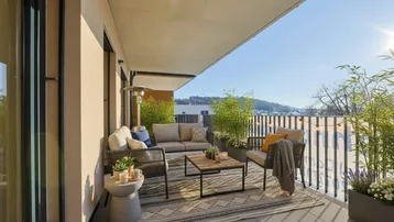 Geräumiger, sonniger Balkon mit bequemen Outdoor-Möbeln und Blick ins Grüne.