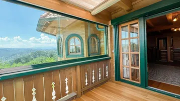 Verglaster Balkon mit atemberaubendem Panoramablick über grüne Hügel und Täler.