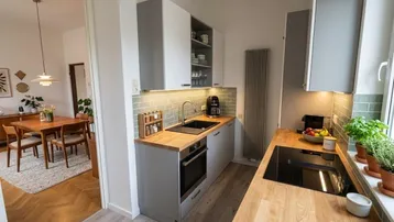 Moderne Küche mit Holz-Arbeitsplatten, grauen Schränken und Blick in den Essbereich, funktional und stilvoll.