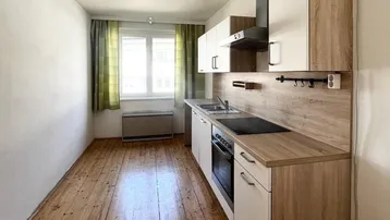 Funktionale Küche mit Holzboden, Einbauschränken und Fenster mit Blick ins Grüne.