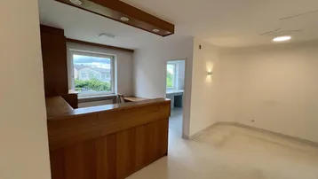 Geräumiger Büroraum mit Holztheke und Blick ins Grüne durch das Fenster, hell und einladend.