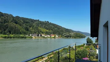 Geräumiger Balkon mit Glasgeländer bietet einen weiten Blick auf den Fluss und die umliegende grüne Landschaft.
