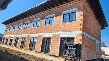 Neubau im Rohbauzustand mit Ziegelmauerwerk und bereits installierten Fenstern und Türen.