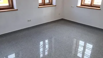 Helles, leeres Zimmer mit drei Holzfenstern und glänzendem Granitboden, bereit für die individuelle Gestaltung.