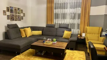Gemütliches Wohnzimmer mit großem Ecksofa, gelben Akzenten und modernem Couchtisch.