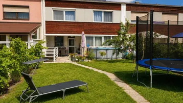 Gepflegter Gartenbereich mit Rasenfläche, Trampolin, Aufstellpool und Terrasse hinter dem Reihenhaus.