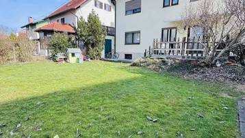 Großer, sonniger Garten mit Rasenfläche und Kinderspielhaus hinter dem Haus.