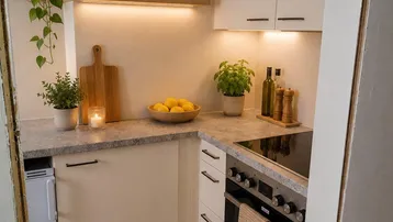 Kompakte Küche mit hellen Schränken, Induktionskochfeld und integriertem Backofen, ideal für kleine Wohnungen.