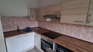 Helle Küche mit Holzfronten, Arbeitsplatte und Fliesenspiegel in Pastellfarben.