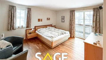 Gemütliches Schlafzimmer mit Holzbett, Parkettboden und Zugang zu einem Balkon, das viel natürliches Licht erhält.
