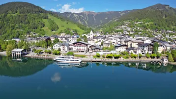 Panoramablick auf die malerische Stadt am See, umgeben von grünen Bergen und klarem Wasser.