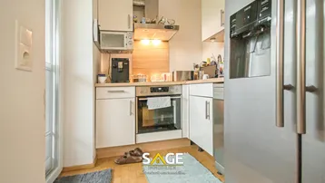 Kompakte Einbauküche mit weißen Schränken, Holztheke und modernen Geräten.