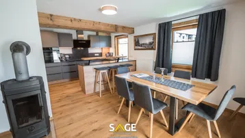 Gemütlicher Essbereich mit Holztisch und Stühlen, angrenzend an die moderne Küche mit Kochinsel.