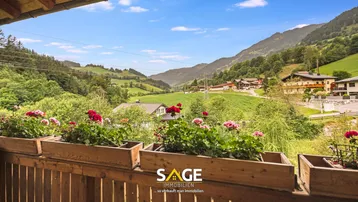 Balkon mit Blumenkästen und weitem Blick auf die umliegende grüne Berglandschaft.