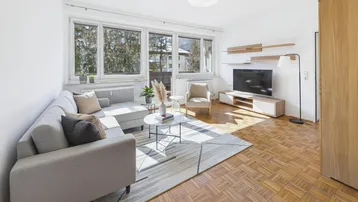 Gemütliches Wohnzimmer mit Parkettboden, großem Fenster und moderner Einrichtung.