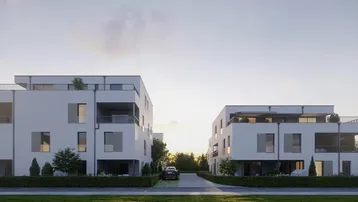 Moderne weiße Gebäude mit Flachdach und großen Fenstern, umgeben von Grünflächen bei Sonnenuntergang.