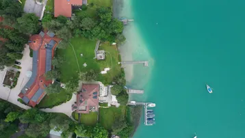 Luftaufnahme eines luxuriösen Anwesens direkt am See mit Bootsstegen und weitläufigen Grünflächen.