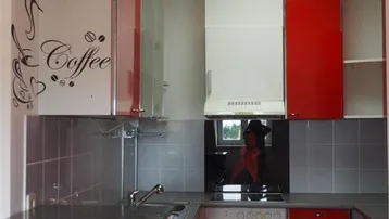 Moderne Küche mit roten und weißen Schränken, grauen Fliesen und dunkler Arbeitsplatte.