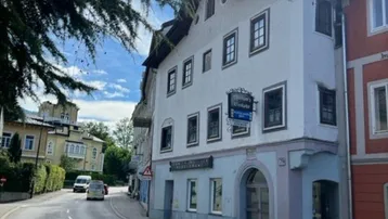 Historisches Gebäude an einer Straße mit traditioneller Architektur und Geschäften im Erdgeschoss.