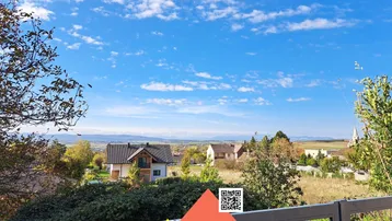 Panoramablick über die umliegende Landschaft mit Häusern und Bergen am Horizont unter blauem Himmel.