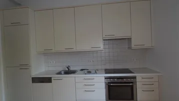 Moderne Einbauküche in hellem Beige mit integrierten Geräten und weißer Fliesenrückwand.