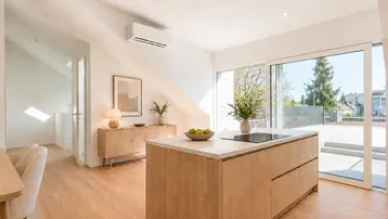 Helle, offene Wohnküche mit Kochinsel, Holzboden und Zugang zur großen Dachterrasse.