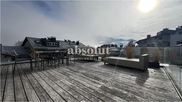 Geräumige Dachterrasse mit Holzboden, Sitzgelegenheiten und weitem Blick auf die umliegende Berglandschaft.