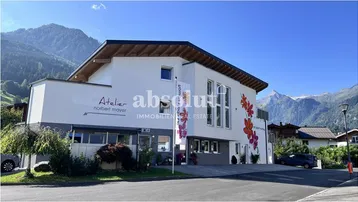 Modernes Gebäude mit weißer Fassade, bunten Blumenmotiven und Bergblick in sonniger Umgebung.