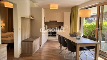 Heller offener Wohnbereich mit Essplatz, integrierter Küche und Zugang zu einem Schlafzimmer.