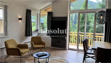 Helles Wohn- und Esszimmer mit großen Fenstern, Holzboden und Bergblick.