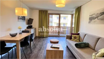 Heller offener Wohn- und Essbereich mit Holzboden, Zugang zum Balkon und Blick auf die Umgebung.