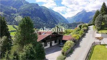 Großzügiges Anwesen in alpiner Landschaft mit beeindruckendem Bergblick und umgeben von viel Grün.