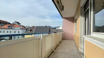 Langer Balkon mit Fliesenboden und Blick auf die umliegende Nachbarschaft.