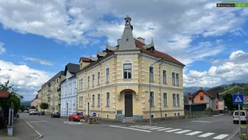 Historisches Eckgebäude mit markanter Architektur und gelber Fassade an einer Straße.