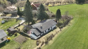 Weitläufige Luftaufnahme des Hauses mit umliegenden Feldern und Wäldern, eingebettet in eine grüne Landschaft.