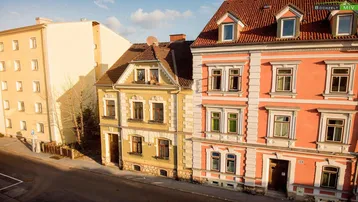 Historische Gebäude mit farbigen Fassaden und Satteldächern an einer Straße.