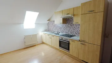 Helle Küche im Dachgeschoss mit Holzfronten, Dachfenster und funktionaler Ausstattung.